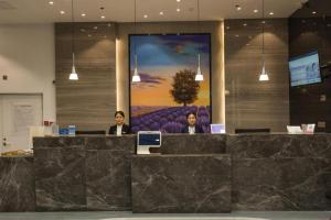 three people sitting at a counter in a lobby at Lavande Hotels Heze Changjiang Road Wanda Plaza in Zhaolou
