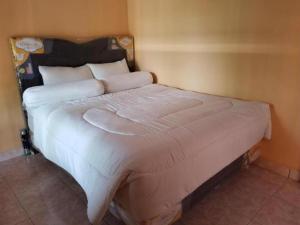 a large bed with white sheets and pillows in a room at Algira Homestay Prambanan in Prambanan
