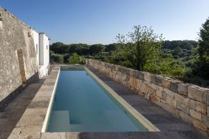 a swimming pool next to a stone wall at TRULOCO NUZZI - LUXURY DOMUS in Locorotondo