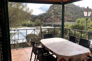 a table and chairs on a balcony with a view of a river at La Casa del Lago in Navas del Rey