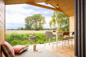 eine Terrasse mit einem Tisch, Stühlen und einem Feld in der Unterkunft ElboTinyhouse in Bleckede