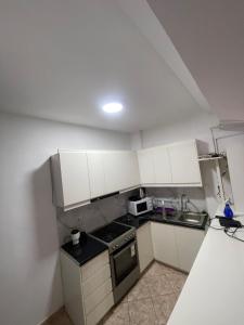a small kitchen with white cabinets and a sink at Cozy Apartment in Sarandë +9 photos