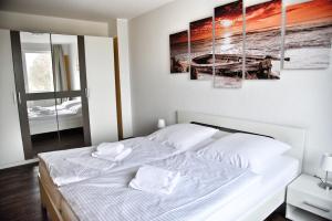 ウッカーミュンデにあるLagunenstadt am Haff Fewo 47 - Kehr wieder!のベッドルーム1室(白いベッド1台、絵画4点付)