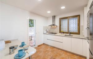 a kitchen with white cabinets and blue cups on a table at Gorgeous Home In Sant Cebrià De Vallalt in Sant Cebrià de Vallalta
