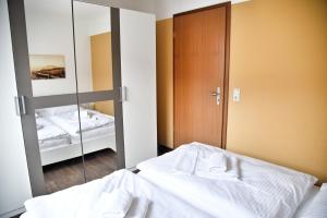 a bedroom with a mirror and a bed with white sheets at Lagunenstadt am Haff Fewo 133 - Hol über! in Ueckermünde