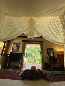 a bedroom with a large bed with a large window at Villa Purnamasari in Ubud