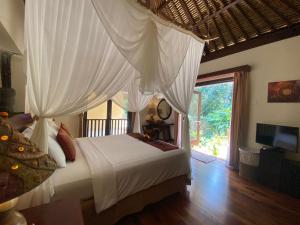 a bedroom with a bed with a canopy at Villa Purnamasari in Ubud