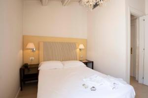 a bedroom with a bed with white sheets and towels on it at Hotel Palazzo Cavalieri in Syracuse