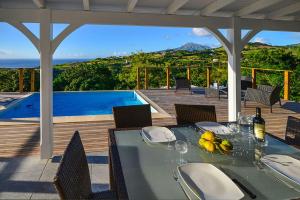 una mesa y sillas en una terraza con piscina en Ti sunset et bungalow 2 chambres, en Le Carbet