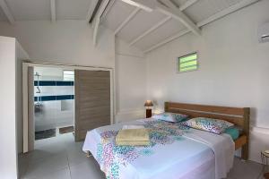Un dormitorio blanco con una cama y una ventana. en Ti sunset et bungalow 2 chambres, en Le Carbet