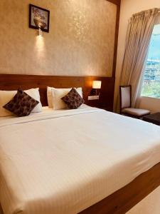 a bedroom with a large white bed with a window at Fortune Hills in Palakkad +41 photos