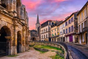a city street with buildings and a tower in the background at Arene Arles Centre in Arles