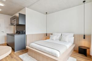 a bedroom with a large white bed and a kitchen at Habyt Berlin Waterfront in Berlin