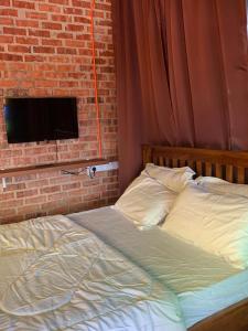 a bed in a bedroom with a brick wall at Balam Inn Homestay & Chalet in Kampong Kebun Baharu
