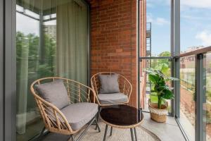 two wicker chairs sitting on a balcony at Scala Apartamenty by Moderna Profit - Łąkowa 60H z parkingiem in Gdańsk