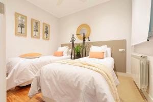sypialnia z 2 łóżkami z białą pościelą i pomarańczowymi poduszkami w obiekcie San Sebastian City Center⎮3 Bedrooms⎮Free WIFI w mieście San Sebastián