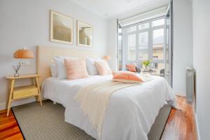 biała sypialnia z dużym białym łóżkiem z różowymi poduszkami w obiekcie San Sebastian City Center⎮3 Bedrooms⎮Free WIFI w mieście San Sebastián