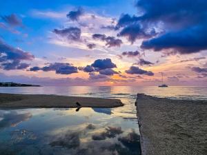 einen Sonnenuntergang am Strand mit einem Boot im Wasser in der Unterkunft Ntina's Apartment in Rhodos (Stadt)