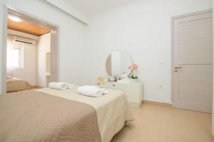 ein weißes Schlafzimmer mit einem Bett und einem Spiegel in der Unterkunft Ntina's Apartment in Rhodos (Stadt)