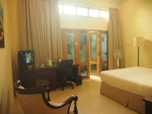 a hotel room with a bed and a desk and a television at The Gecho Inn Town in Jepara