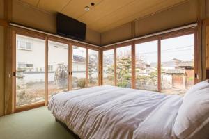 FARMSTAY miyuki-street "Hotaru" في Kugumiya: غرفة نوم بسرير كبير ونوافذ كبيرة