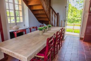 une grande table en bois avec des chaises rouges et une grande pièce dans l'établissement La Petite Maison Garde Barrière, à Baudrières