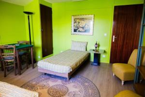 - une chambre avec des murs verts, un lit et une table dans l'établissement La Petite Maison Garde Barrière, à Baudrières