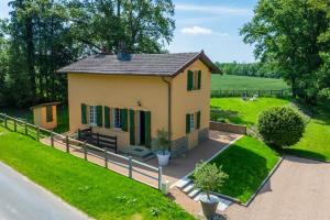 une petite maison jaune avec une clôture et de l'herbe dans l'établissement La Petite Maison Garde Barrière, à Baudrières