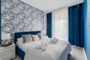 Un dormitorio azul con una cama con una pared azul. en Horyzont Apartamenty -Bałtycka2 - SAUNA & FITNESS - ŚNIADANIA, en Kołobrzeg