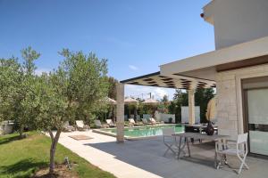 a patio with a table and chairs next to a pool at W Villas Halkidiki in Pefkochori
