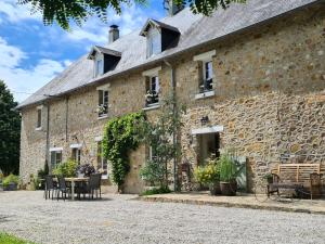 a stone building with tables and chairs in front of it at La Maison des Tilleuls in Saint-Germain-sur-Sèves