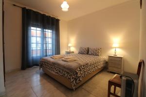 a bedroom with a bed and a large window at Casa Cor-de-Rosa in Vila Nova de Milfontes