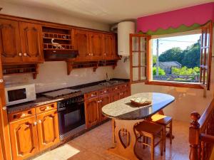 a kitchen with wooden cabinets and a table and a window at LA CAMELIA in Pontevedra