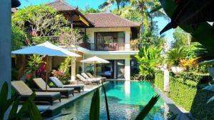 a villa with a swimming pool in front of a house at Villa Saraswati in Ubud
