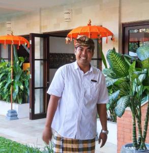 a man wearing a hat with an umbrella on his head at Villa Saraswati in Ubud