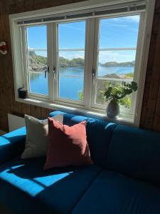 a blue couch with pillows in front of a window at Lofoten Sea Lodge in Sennesvik