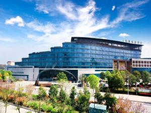ein großes Glasgebäude vor einem Parkplatz in der Unterkunft Wuhan Gleetour Hotel in Wuhan