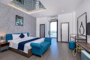 a bedroom with a large bed and a blue chair at Joi Home Beachfront in Vung Tau