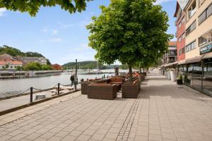 un marciapiede con sedie e alberi accanto a un fiume di Thon Hotel Halden a Halden