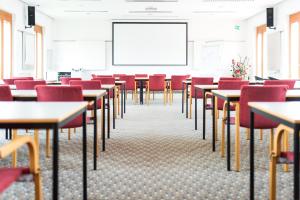 an empty classroom with tables and chairs and a whiteboard at Hotel Raffel in Jennersdorf