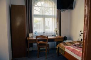 a bedroom with a desk and a bed and a window at ''Zatoka" in Bydgoszcz