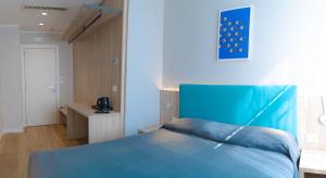 a bedroom with a blue bed and a desk at Hotel Tritone in Trieste