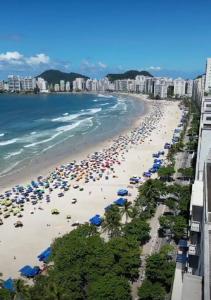 une plage avec des parasols et des foules de gens dans l'établissement Guaruja Pitangueiras apto na praia, à Guarujá