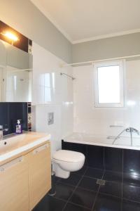 a white bathroom with a toilet and a sink at Aris Apartment in Peratiá