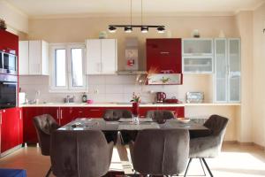 a kitchen with a table and chairs and red cabinets at Aris Apartment in Peratiá +21 photos