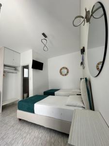 a white bedroom with a bed and a mirror at Theodora Rooms in Kamarai