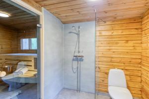a bathroom with a toilet and a glass shower at Pinetree Cottages Sunny cabin in Pyhäranta