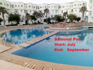 a large swimming pool in front of a building at Stylish Duplex - Ocean View - Airport - Wifi - renovated 2025 - 24h reception in Jbila