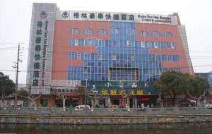 a large building next to a body of water at GreenTree Inn Yangzhou Baoying South Anyi Road Express Hotel in Baoying