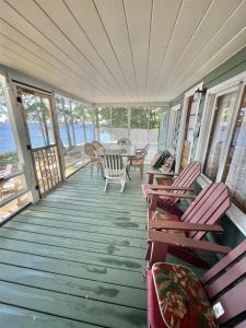 a porch with rocking chairs and a table on it at PLACYD PINES LIMIT 8 cottage in North Sebago +21 photos